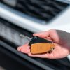 A hand holding a car key near a vehicle